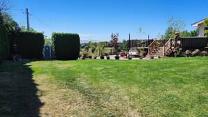 A well-maintained backyard with a lawn, a wooden deck, and a small garden area. - Beautiful 2-bedroom apartment with AC in College Place (College Place)