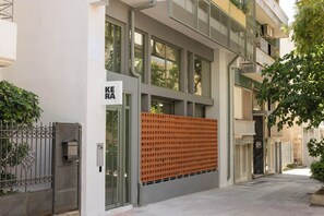 Um edifício moderno com fachada de vidro extensa, portão de metal e uma placa com a inscrição 'KEA'.