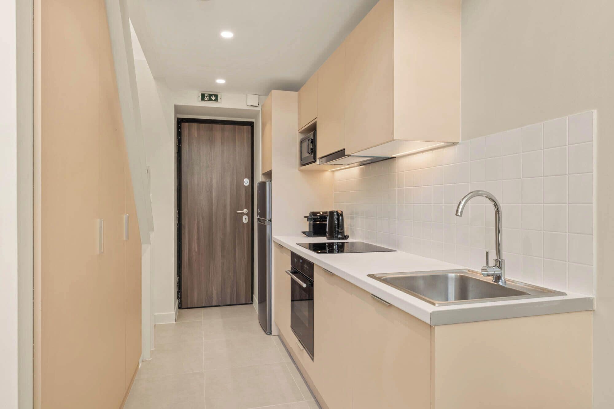 Una cucina moderna con forno integrato, lavello in acciaio inossidabile e microonde.