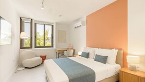 A modern bedroom with a large bed, a desk, and a chair.