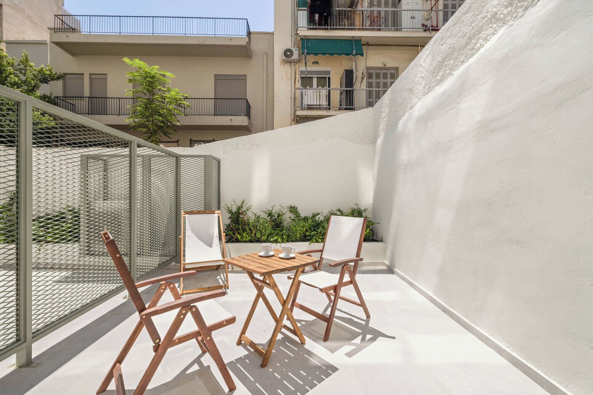 Una terrazza sul tetto con tavolo e sedie, circondata da un muro bianco e una recinzione in metallo.