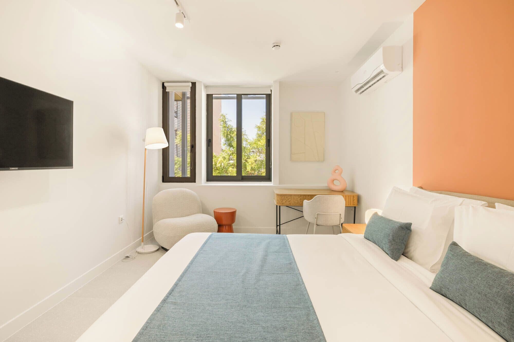 Una camera d'albergo con un letto, una scrivania, una sedia e una televisione.