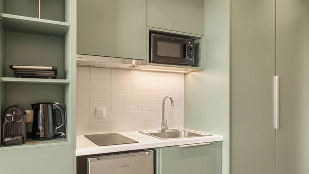 A compact kitchen with a microwave, kettle, and a dishwasher. - Kera by Zoia Living (Athens)
