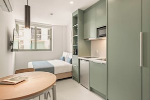 Une cuisine compacte équipée d’un four à micro-ondes, d’un lave-vaisselle et d’un petit coin repas avec une table et des chaises.
