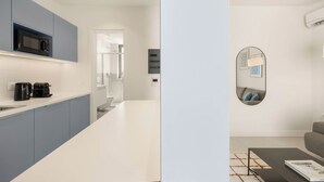 A modern kitchen with grey cabinets, a black microwave, and a coffee maker. - Kera by Zoia Living (Athens)