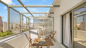 Un balcón con una mesa, sillas y un ventanal de vidrio que da a un espacio interior.