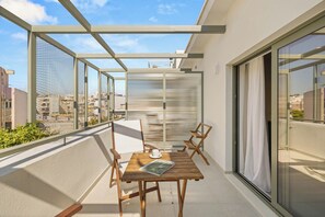 Uma varanda com mesa, cadeiras e porta de vidro que dá para um espaço interno.