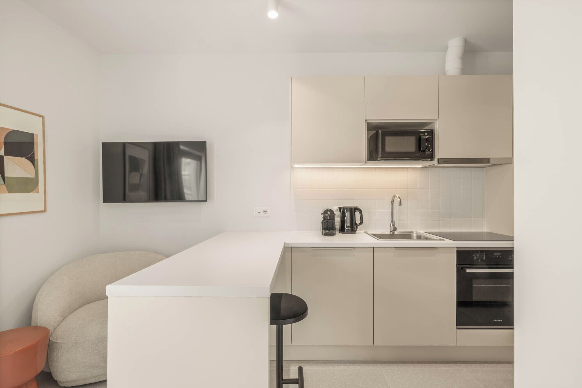 A modern kitchen with white cabinetry, a microwave, a coffee maker, and an oven.