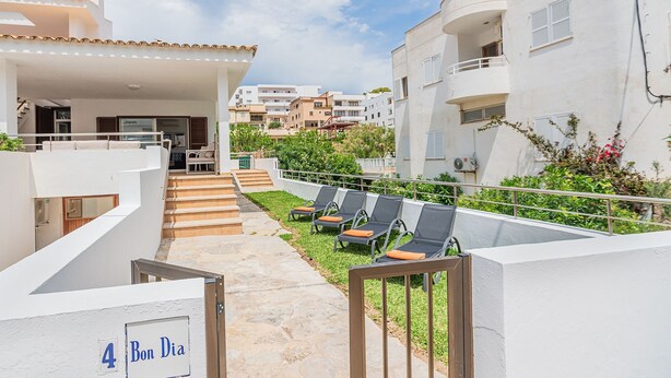 A residential building with a covered outdoor area, a staircase, and a row of sun loungers. - Cosy Beach Apartment, Cala Sant Vicenc (Pollença)