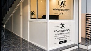 A modern Aidan Residency building with a glass facade, a staircase, and a sign indicating premium AC rooms. - Hotel Aiden Residency Aluva (North Paravur)