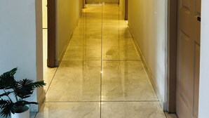 A hallway with a tiled floor, doors on both sides, and a potted plant at the end. - Hotel Aiden Residency Aluva (North Paravur)