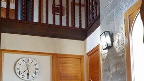 Una habitación con puerta de madera, un reloj en la pared, un refrigerador y piso de baldosas.