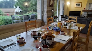 Un coin repas avec une table mise pour le petit-déjeuner, un téléviseur et une vue sur l’extérieur.