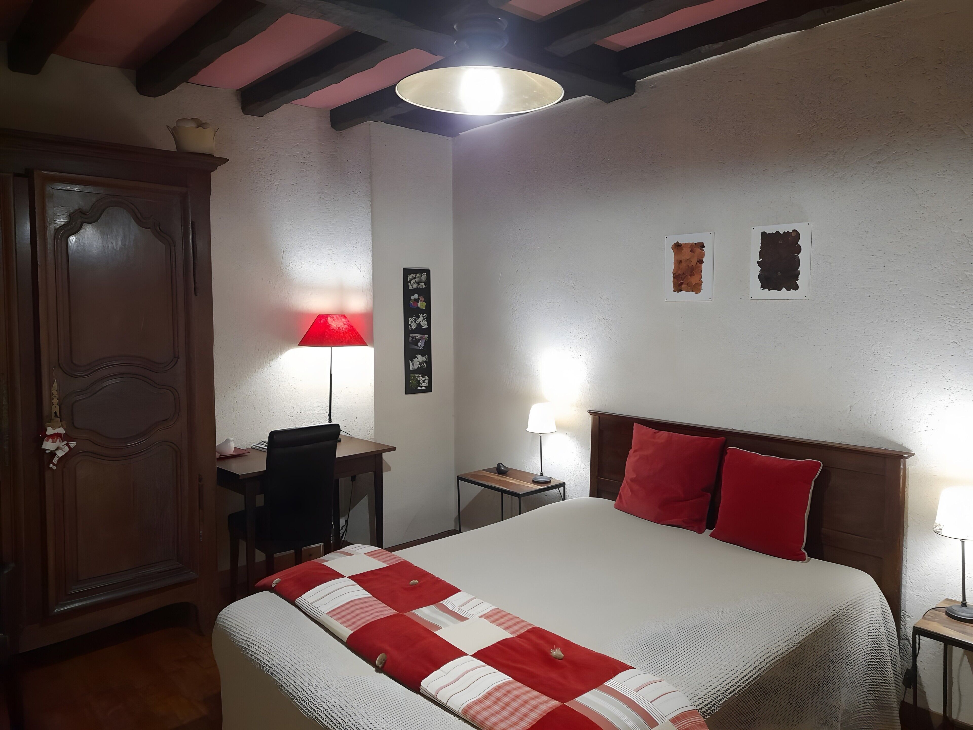 Une chambre à coucher comprenant un lit, un bureau, une chaise, une armoire et un mur décoré de tableaux.