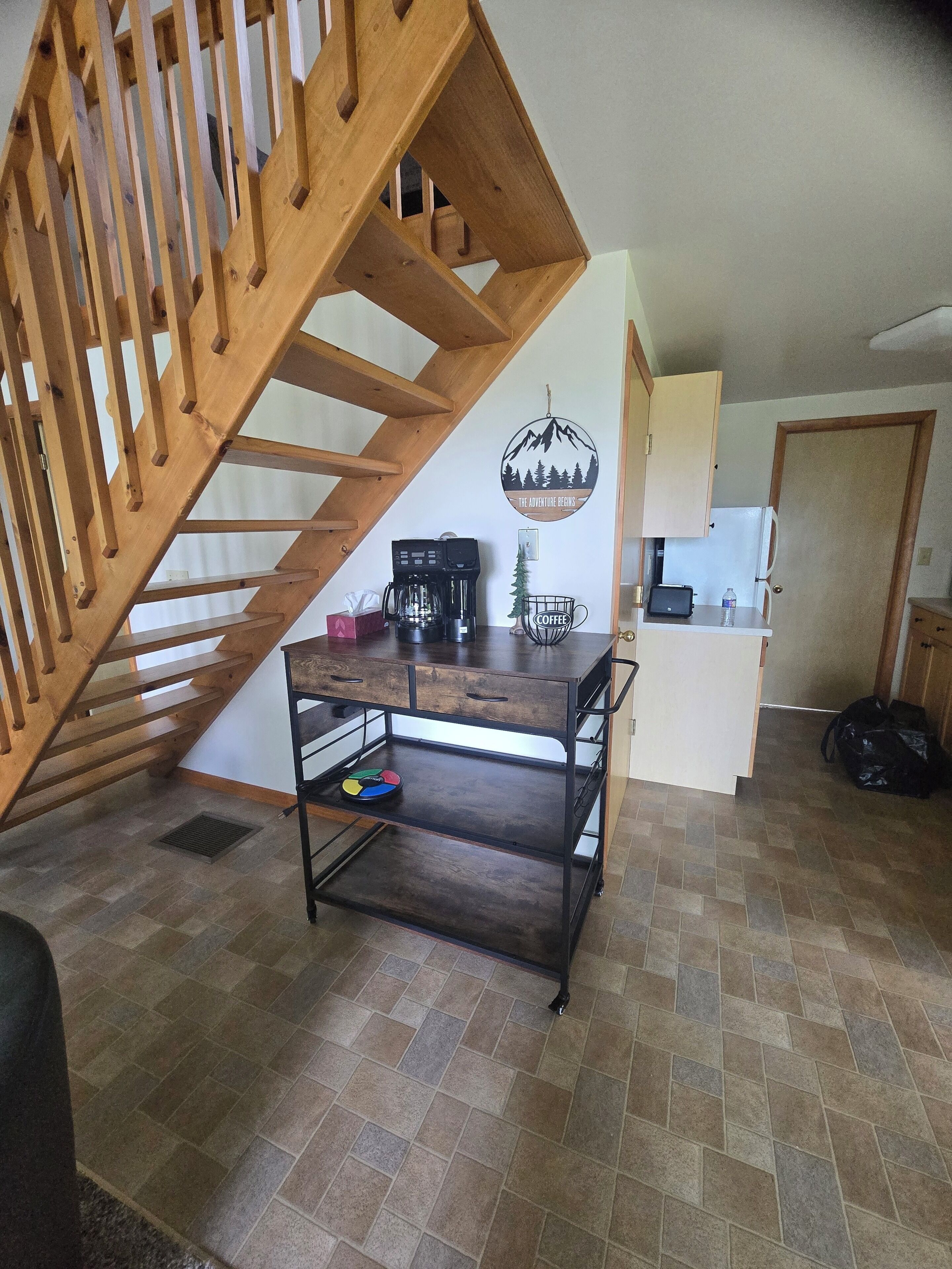 Una cocina con una escalera de madera, una estación de café y un letrero en la pared.