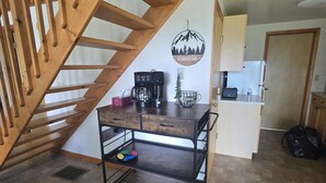Una cucina con una scala in legno, un angolo caffè e un cartello appeso al muro.