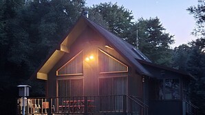 Una baita di legno con un portico e una terrazza recintata.