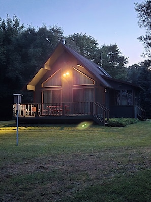 A wooden cabin with a porch and a fenced deck area. - Bluff Point Hideaway Private & Cozy 2 Bedroom Cabin (Keuka Park)