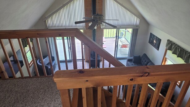 Una scala in legno con una ventola a soffitto, che porta a un balcone con mobili da esterno.