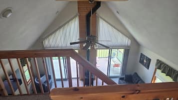 Una escalera de madera con un ventilador de techo, que conduce a un balcón con mobiliario exterior.