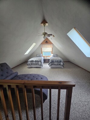 An attic bedroom with a sloped ceiling, two beds, a ceiling fan, and a window. - Bluff Point Hideaway Private & Cozy 2 Bedroom Cabin (Keuka Park)