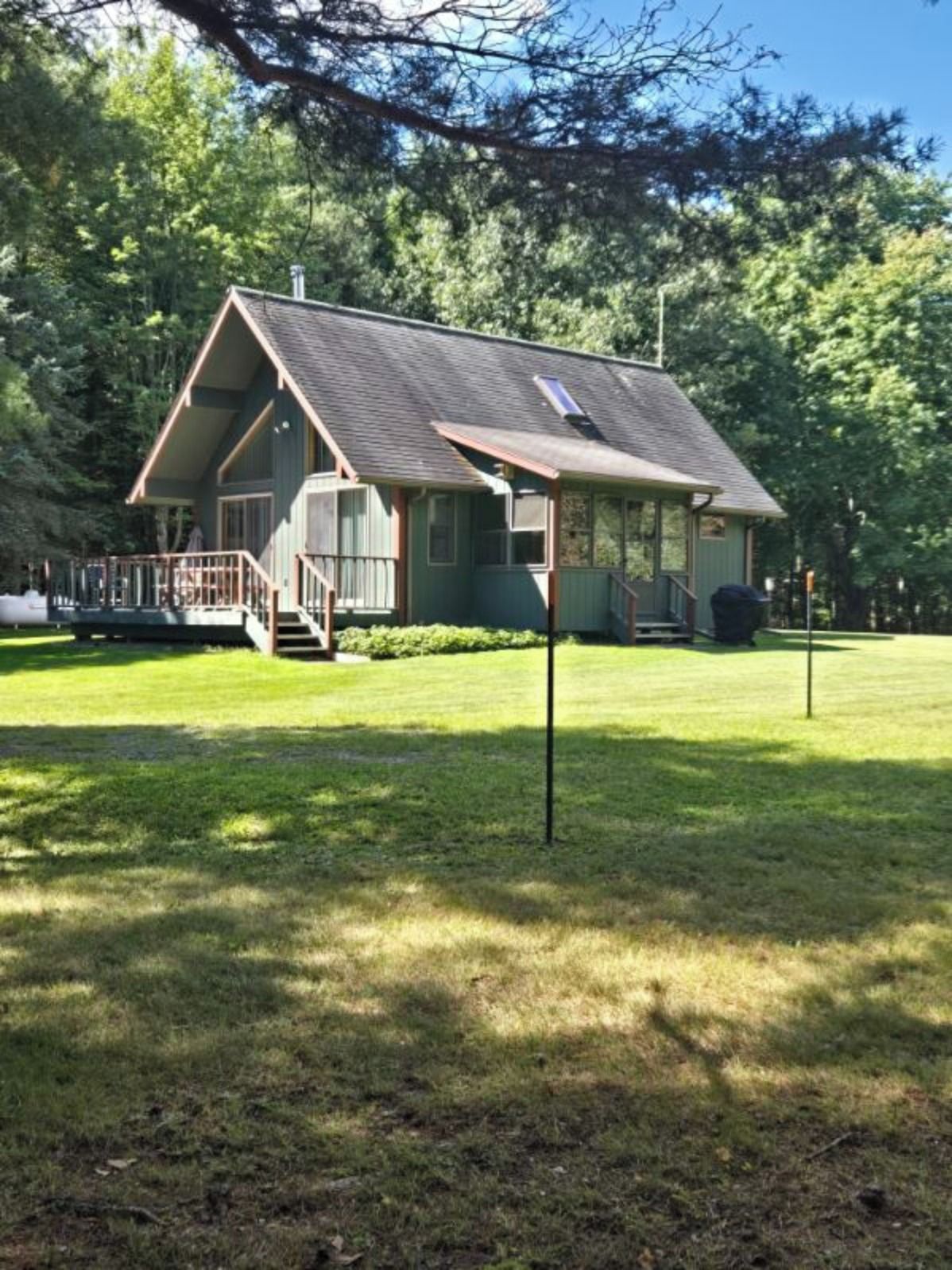 A single-story building with a porch, a small deck, and a grassy yard.