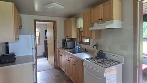 Una cucina con mobili in legno, un fornello, un forno a microonde e un tostapane.
