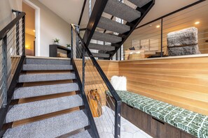 Eine Treppe mit gemusterten Stufen und Holzoptik, die zu einer Ebene mit einer Sitzbank und einem flauschigen weißen Kissen führt.