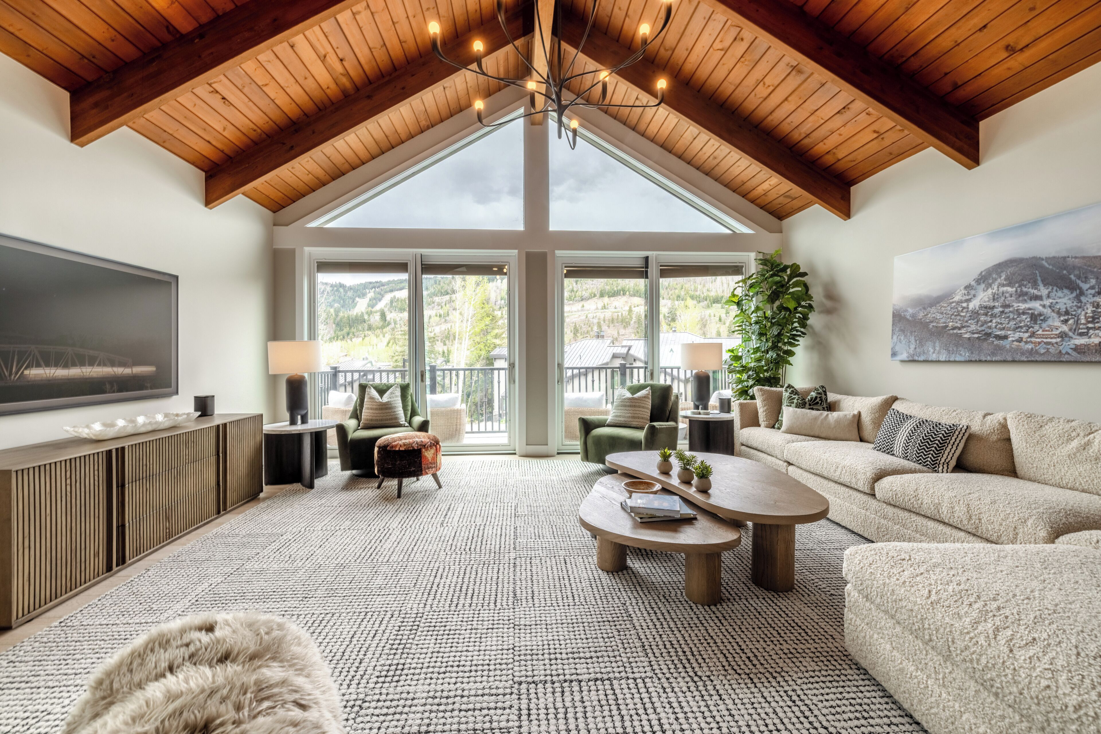 A spacious living room with a high ceiling, large windows, and a view of the outdoors.