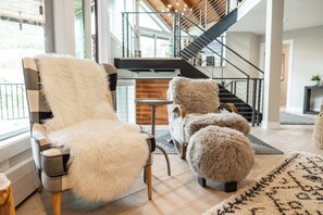 A modern living room with a large window, a staircase, and a fluffy chair. - Designer Pinnacle Home with Free DV Shuttle (Park City)