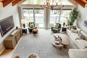 A cozy living room with a large TV, comfortable seating, and a view of the outdoors.