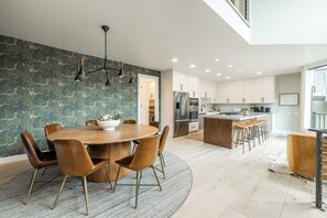A modern kitchen with white cabinets, stainless steel appliances, and a central island with bar stools. - Designer Pinnacle Home with Free DV Shuttle (Park City)