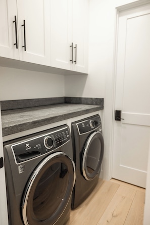 A laundry area with two front-loading washing machines and a countertop.