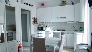 A modern kitchen with white cabinets, a dining table with chairs, a microwave, and a gas stove. - Family-friendly vacation home just a 5-minute walk from the beach (Civitanova Marche)