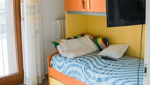 A bedroom with a bed, a television mounted on the wall, and a chair. - Family-friendly vacation home just a 5-minute walk from the beach (Civitanova Marche)