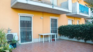 A courtyard with a white table and chairs, a potted plant, and a wall-mounted air conditioner. - Family-friendly vacation home just a 5-minute walk from the beach (Civitanova Marche)