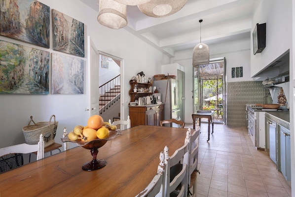 A kitchen with a wooden island, a dining table, and a staircase leading to another level.