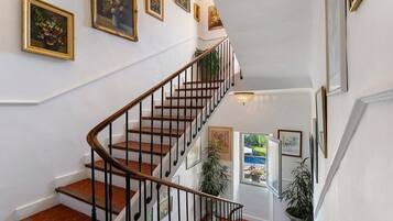A staircase with a wooden handrail and black balusters, leading to an upper level with a view of a pool.