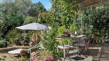 An outdoor patio with a table, chairs, and an umbrella.