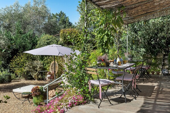 Un patio exterior con mesa, sillas y una sombrilla.