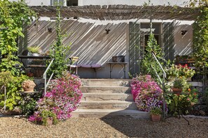 A building with a staircase leading to a door, surrounded by potted plants and flowers.