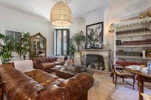 A traditional living room with leather sofas, a fireplace, a bookshelf, and a large mirror.