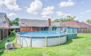 Ein Garten mit Swimmingpool, einer Holzterrasse und einem Ziegelhaus.