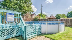 Ein Garten mit Pool, einem eingezäunten Bereich und einer Holzterrasse.