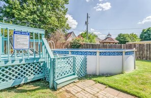Ein Garten mit Pool, einem eingezäunten Bereich und einer Holzterrasse.