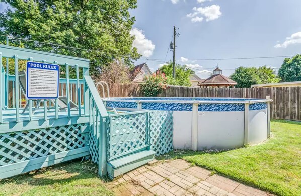 A backyard with a pool, a fenced area, and a wooden deck.