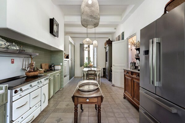 Una cocina con una estufa antigua, un refrigerador moderno y una mesa de comedor con sillas.