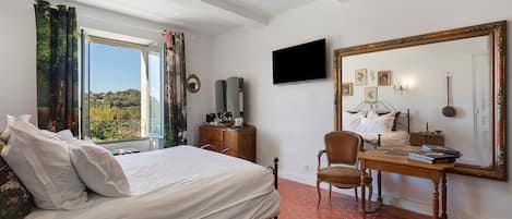 Un dormitorio con una cama, un escritorio, una silla, un televisor y un espejo grande.