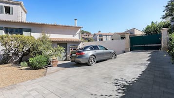 Una zona residencial con camino de entrada pavimentado, un coche aparcado y un acceso con portón.