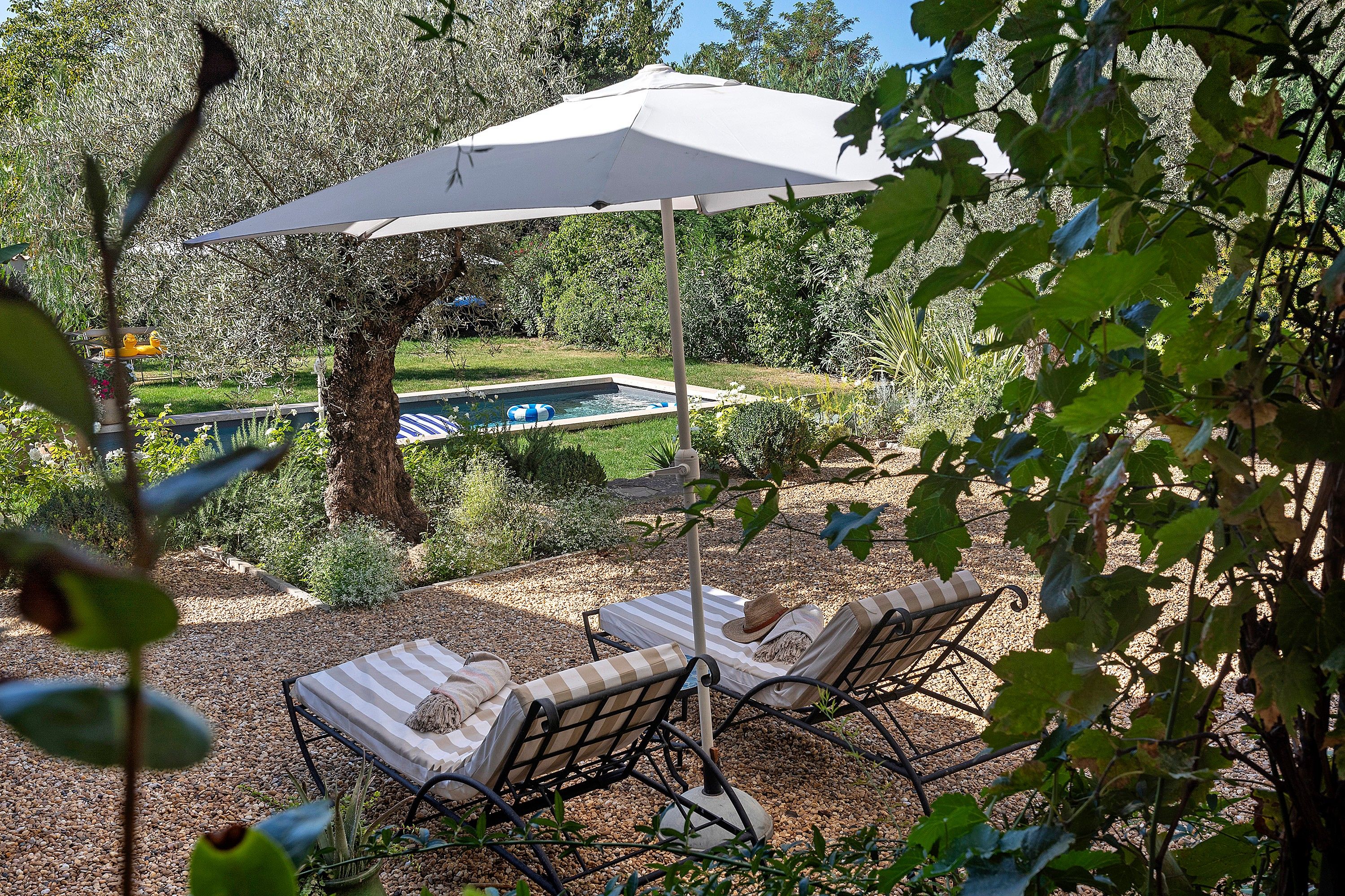 A pool area with two lounge chairs and a large umbrella.